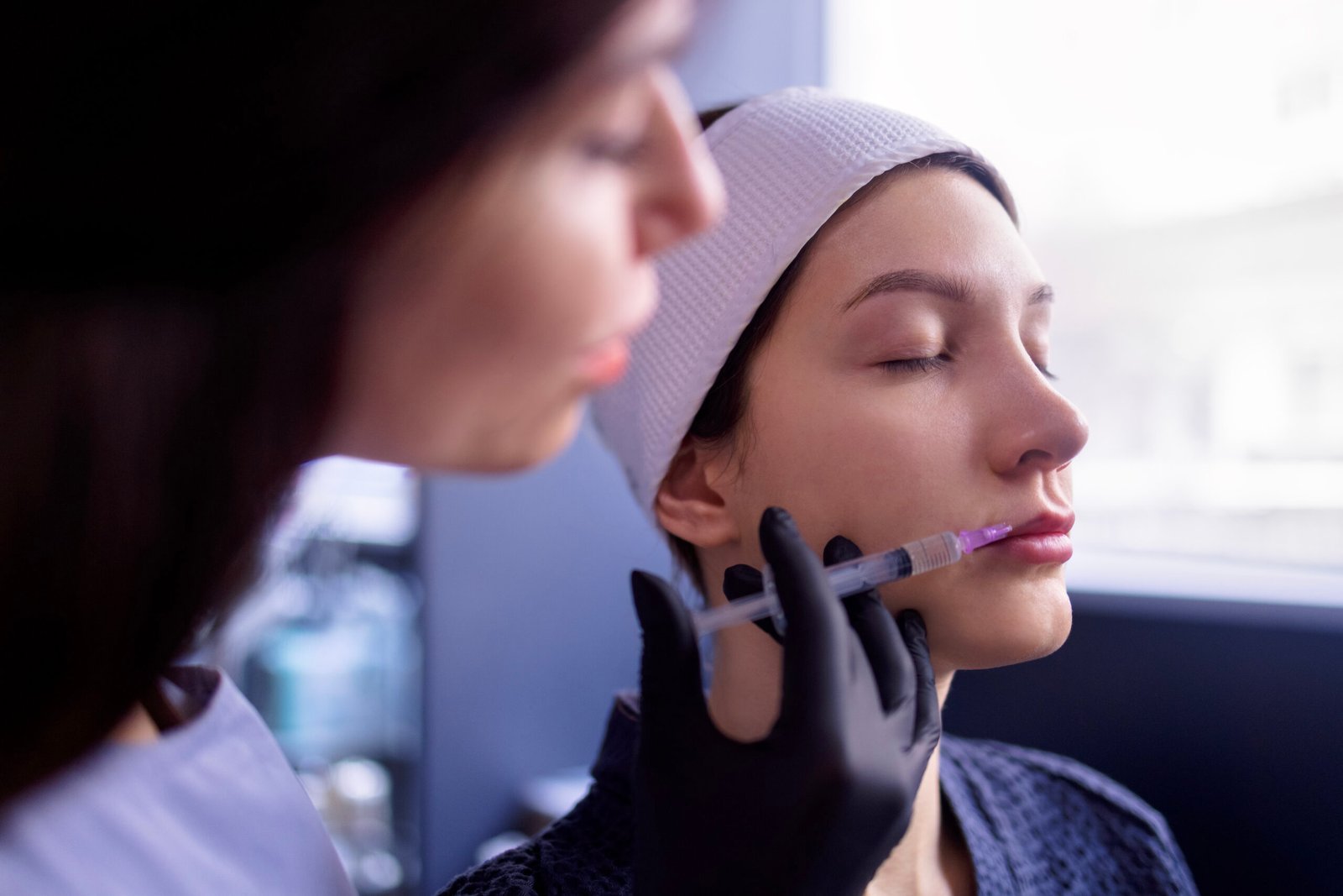 Female cosmetologist performing beauty lip filler injection at Couture Dermatology